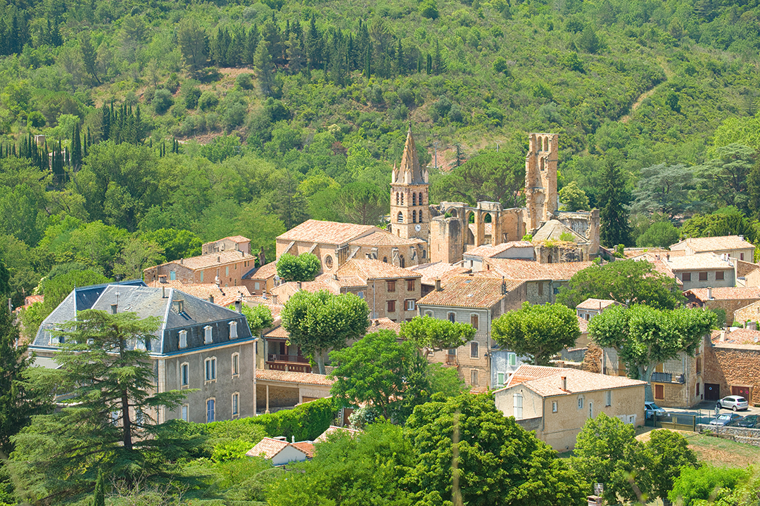 Alet les Bains, Aude, France Abbaye et tour de ruine. Flèche d'église avec horloge. Grande maison au toit mansardé. Maisons en pierre méditerranéennes aux toits de tuiles de terre cuite.
